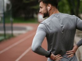 Exercising with sciatica: Image shows man in sports gear holding lower back