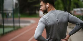 Exercising with sciatica: Image shows man in sports gear holding lower back