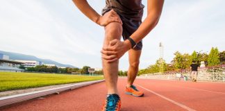 a photo of a runner holding his injured knee