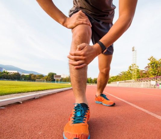 a photo of a runner holding his injured knee