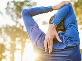 Why do muscles get sore after exercise? Image shows man stretching