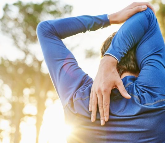 Why do muscles get sore after exercise? Image shows man stretching
