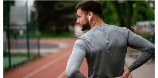 Sciatica: Man holding his lower back in pain during workout on a running track