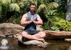 Breathing exercise: Chris Hemsworth meditating with palms together and legs crossed in a river