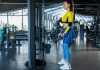 Woman in the gym holding a tricep rope on a cable pulley performing a cable pull through