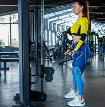 Woman in the gym holding a tricep rope on a cable pulley performing a cable pull through