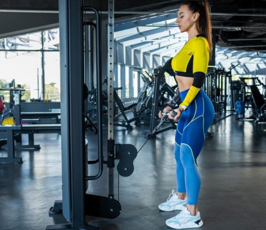 Woman in the gym holding a tricep rope on a cable pulley performing a cable pull through
