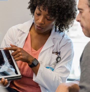 A photo shows an orthopedist showing an x-ray to a patient.