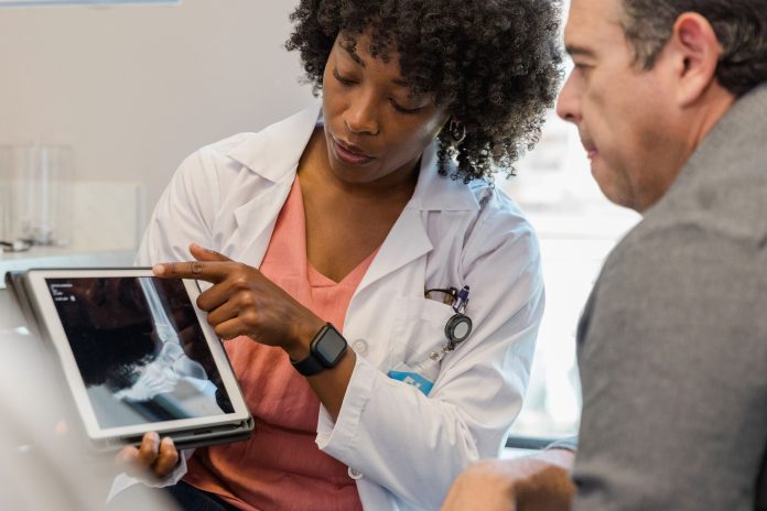 A photo shows an orthopedist showing an x-ray to a patient.